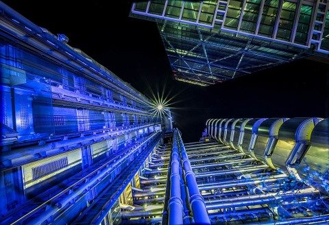 London Architecture night scene looking up at Lloyds Building skyscraper and modern office building in lights.