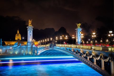 pont bridge alexandre III in paris at night with boat lights on the Seine River