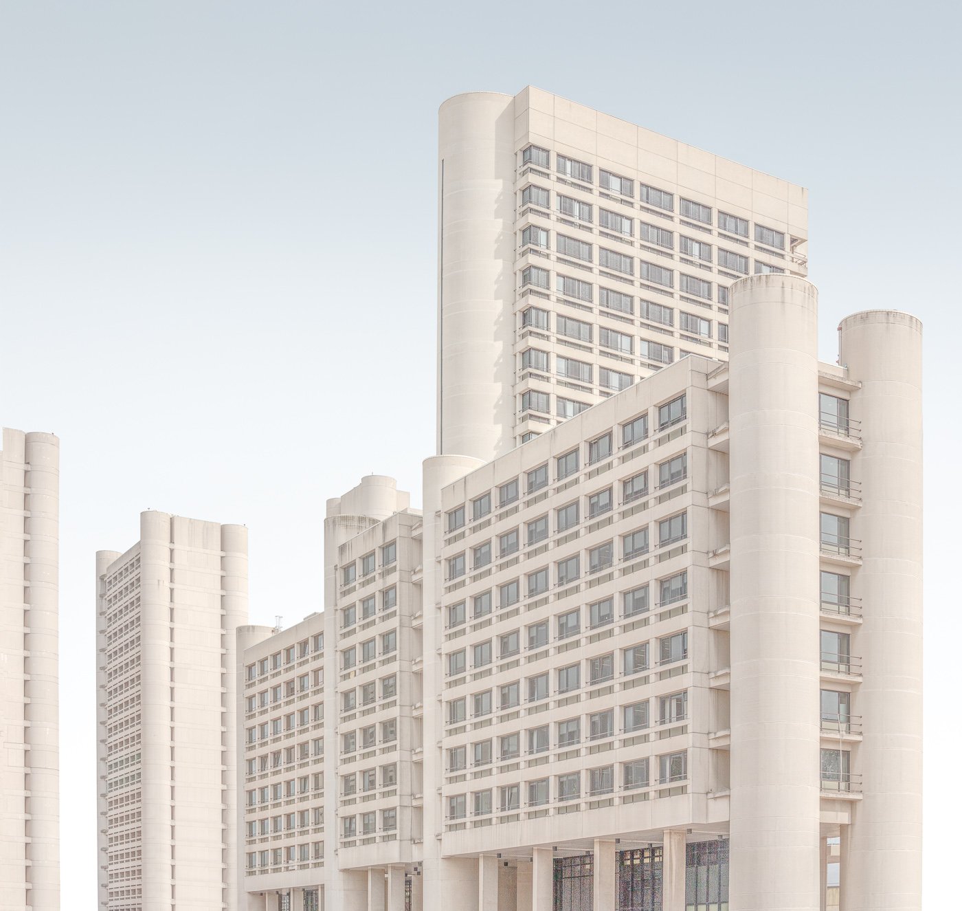 Pale modernist tower blocks layered in a high-key architectural composition.