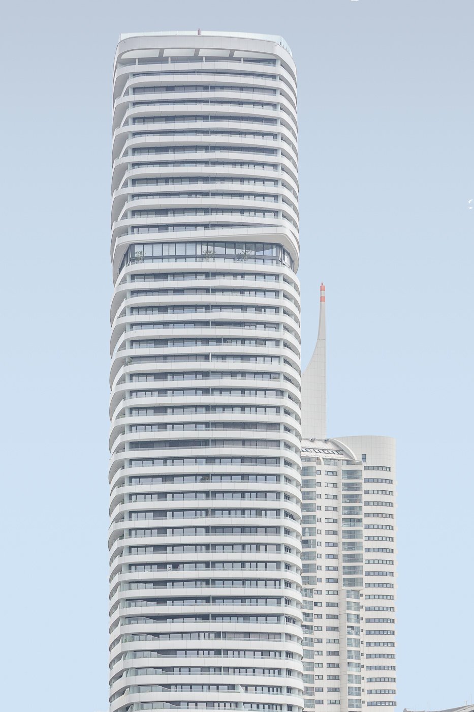Pale curved high-rise towers isolated against a light blue sky.