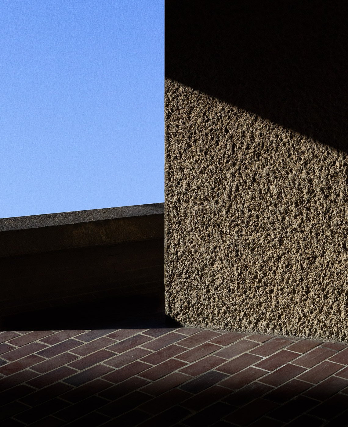 Brutalist concrete textures forming simple geometric planes against blue sky.