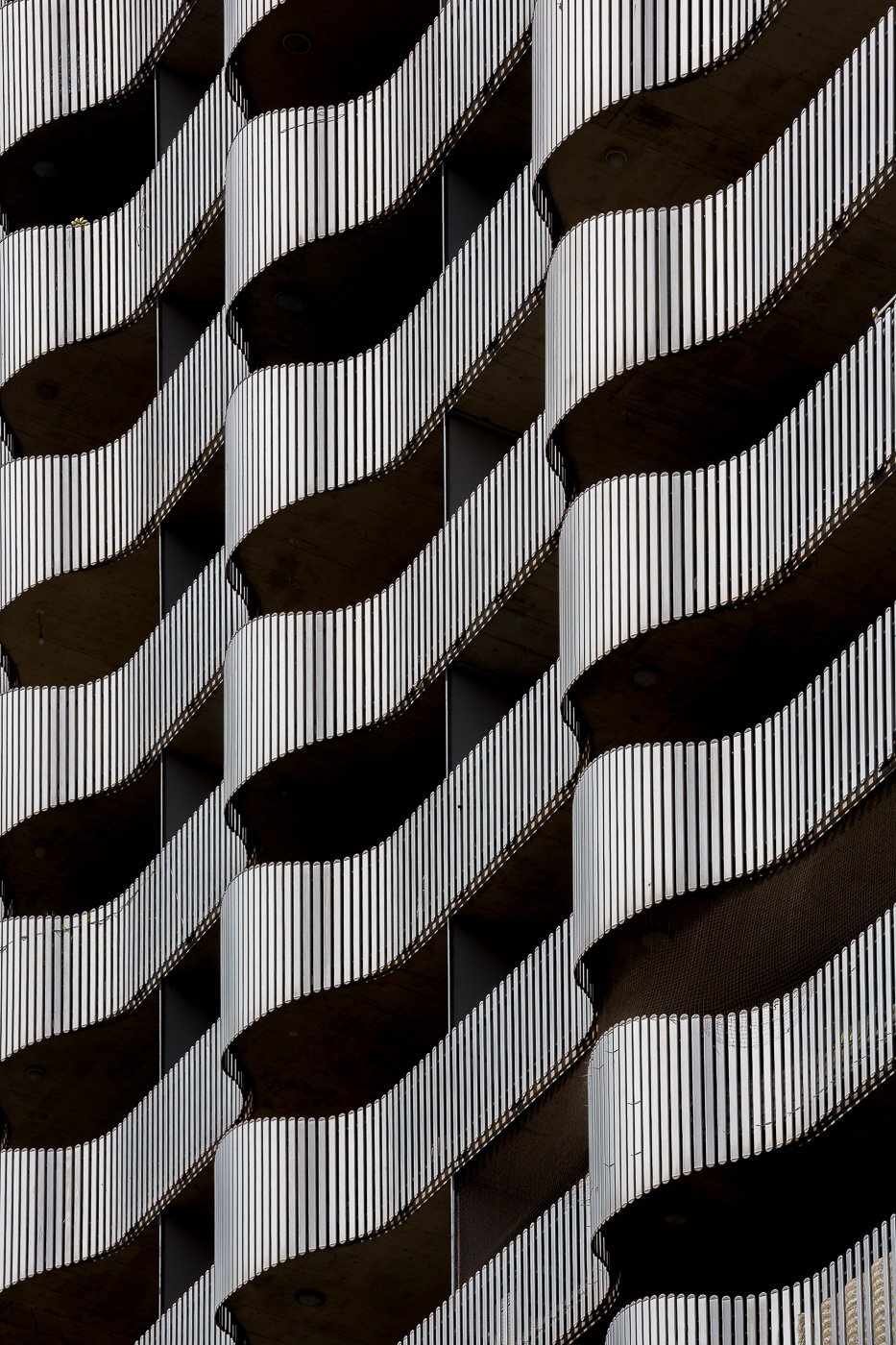 Repeating dark curved balconies against fine vertical architectural lines.