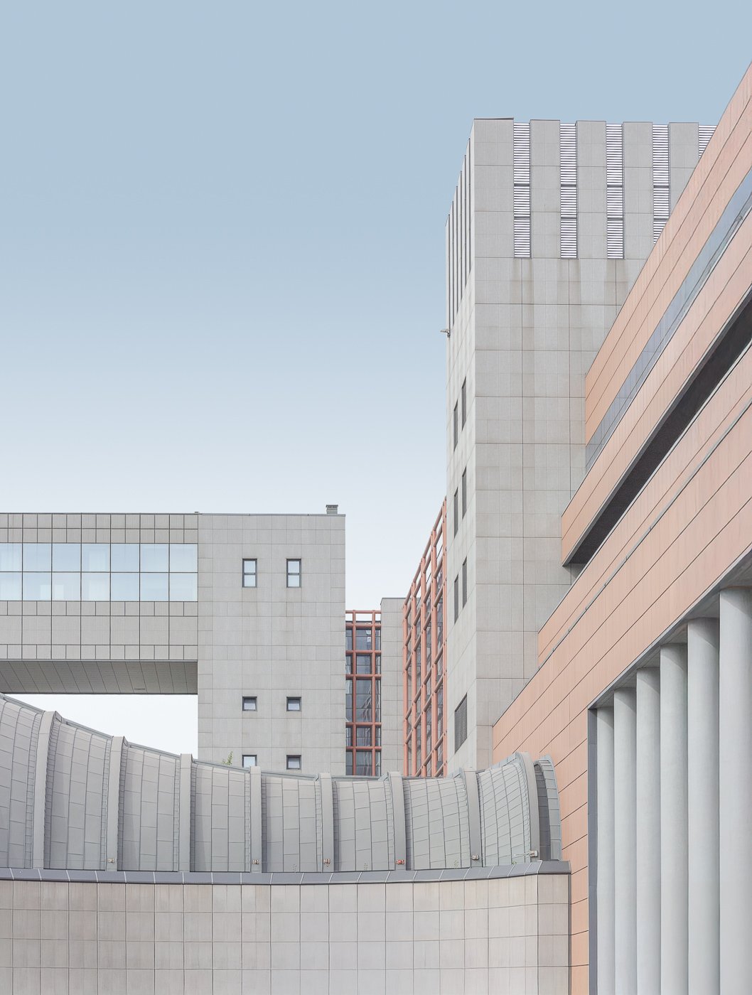 Modern buildings framing a rectangular skybridge in a pale urban composition.