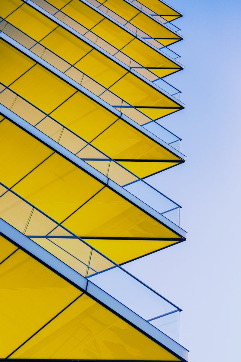 Bright yellow angular canopies with blue structural lines against a pale sky.