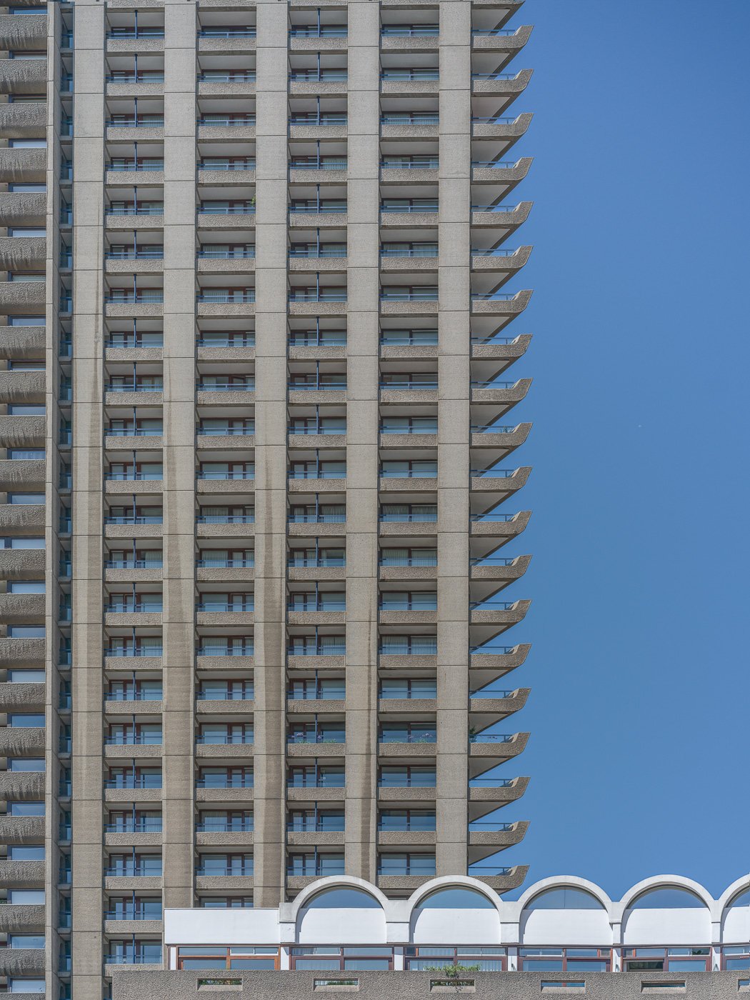 Repeating balconies on a residential tower against blue sky.