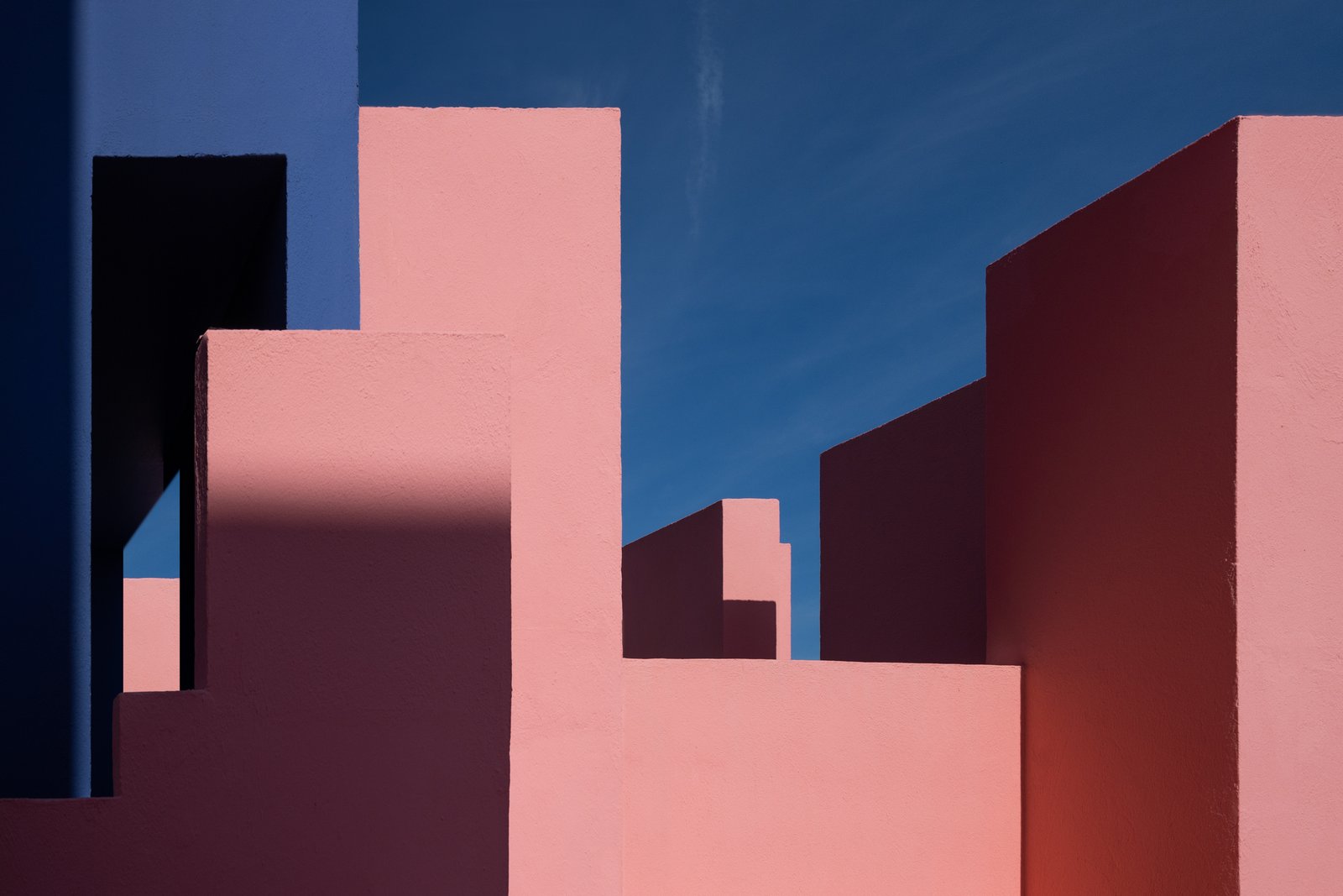 Pink geometric building forms against a deep blue sky.