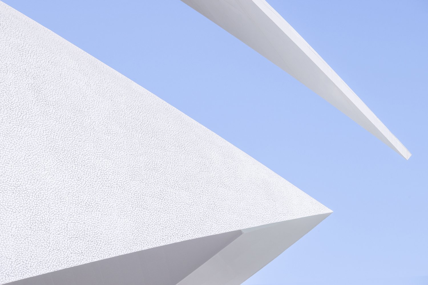 White diagonal architectural beams and planes crossing a pale blue sky.