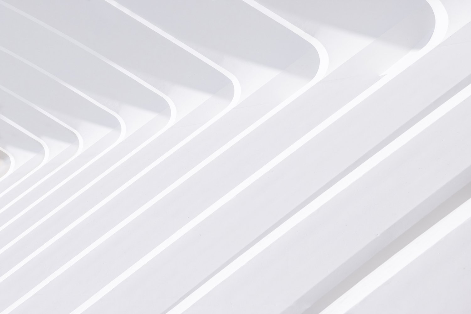High-key white repeating architectural ribs receding diagonally across the frame.