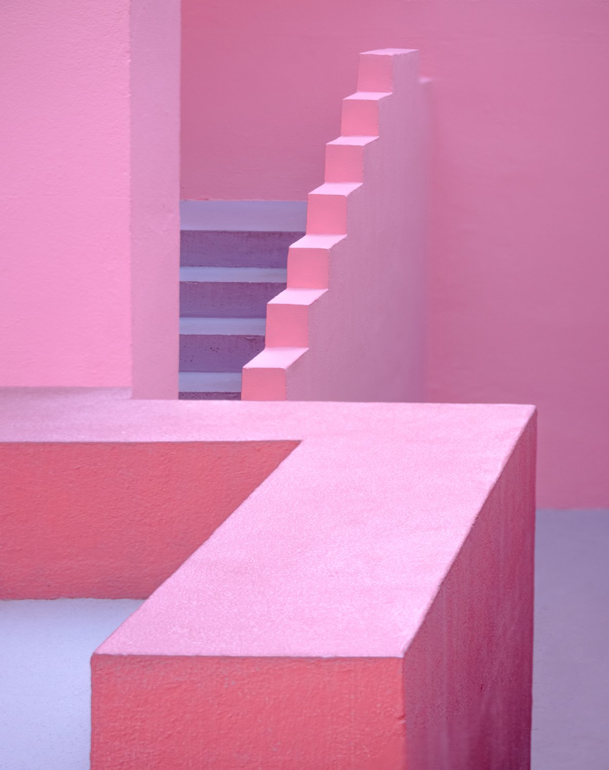Pastel pink architectural forms with a stepped opening and strong geometric shadows.